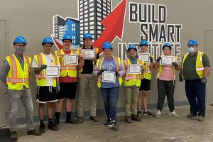 student group with certificates with the Build Smart Institute logo in the background.