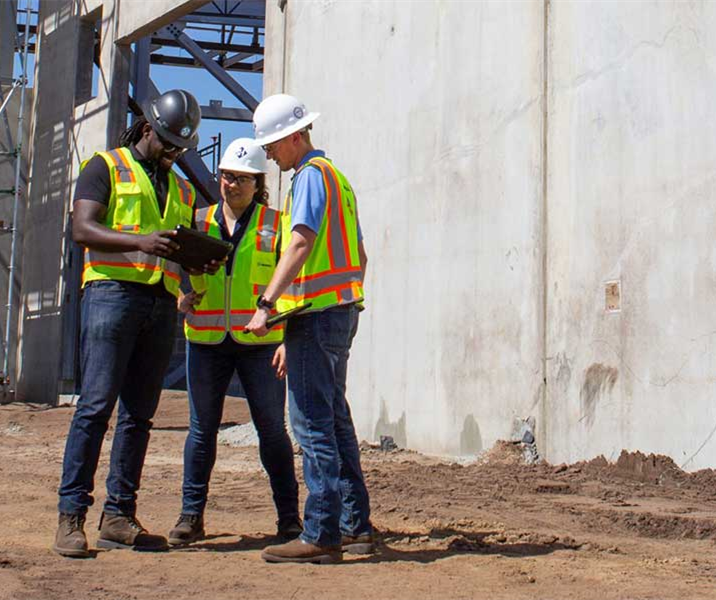 three construction workers standing on a job site in hard hats