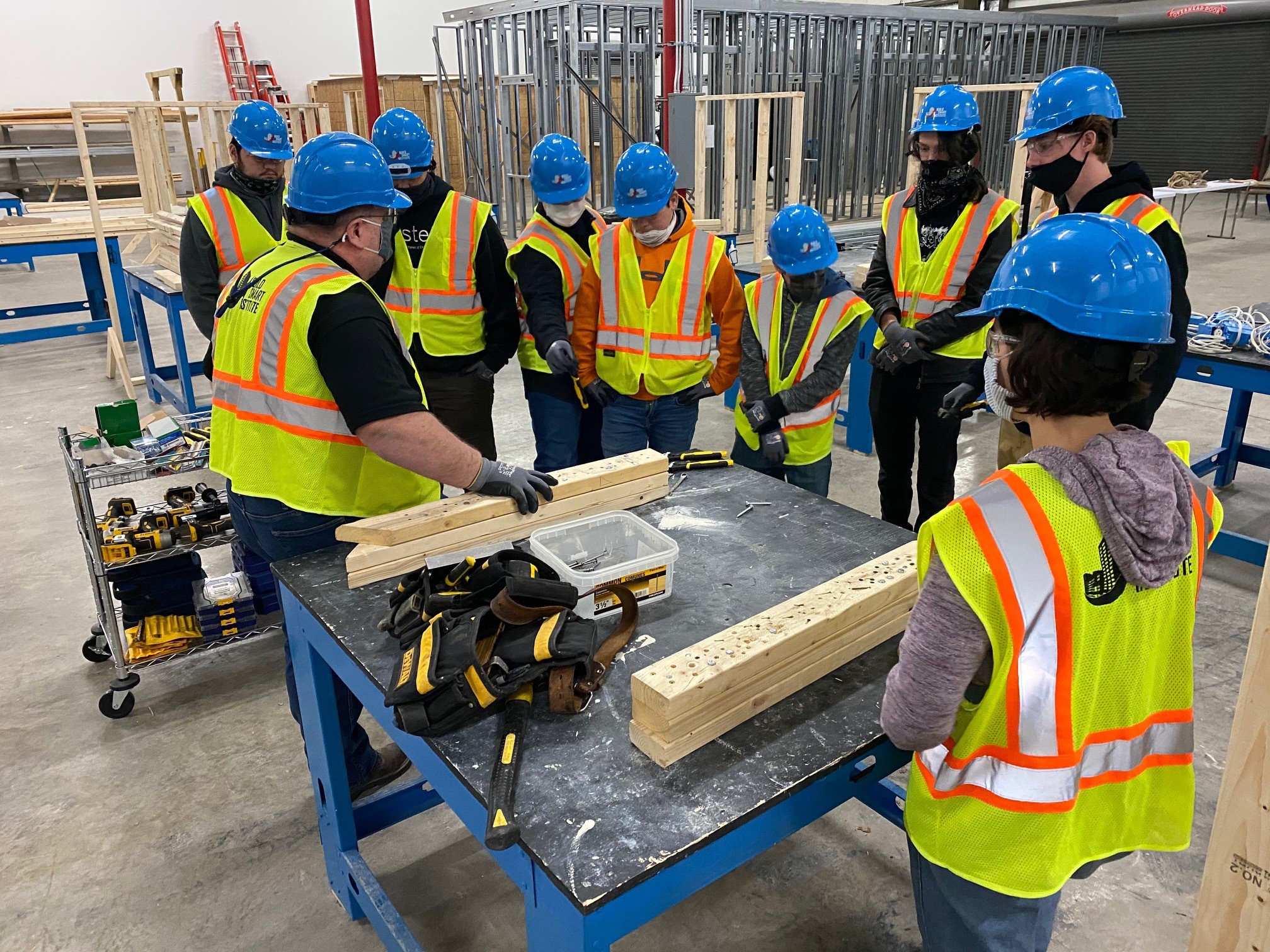 Students gathered around a workbench receiving instructions from an instructor.