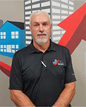 Curtis West standing in front of the Build Smart Institute Logo