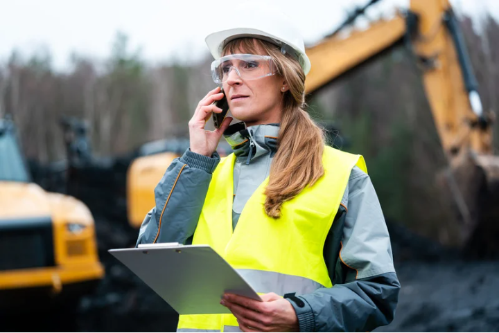 Female construction worker talking on phone while at a job site.