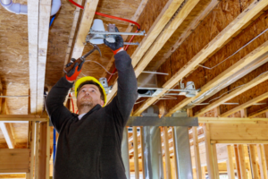 Electrician working to run wiring in the ceiling of new construction.