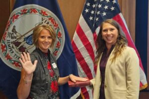 Michelle Ramaker pictured in front of the Virginia and US Flags with Secretary Gee.