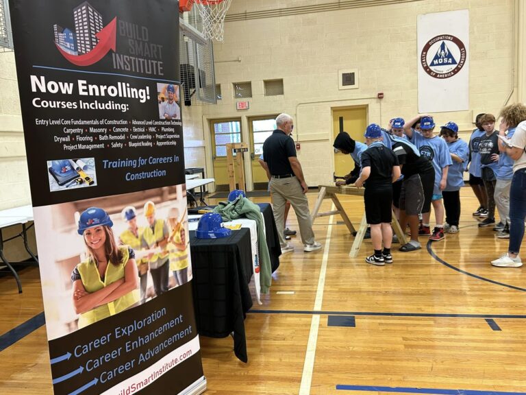 Photo of the Build Smart Display at an expo in a middle school gymnasium with students in the background.