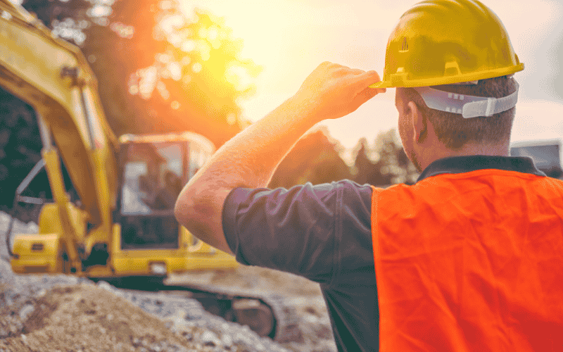 Man in a hard hat watching someone run a dozer.